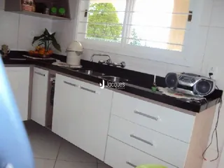 Cozinha com armários brancos e bancadas escuras.