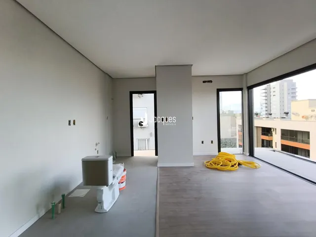 Ambiente interno de uma sala com paredes brancas e piso claro.