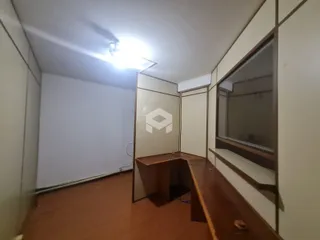 Interior de uma sala com piso de madeira e paredes brancas.