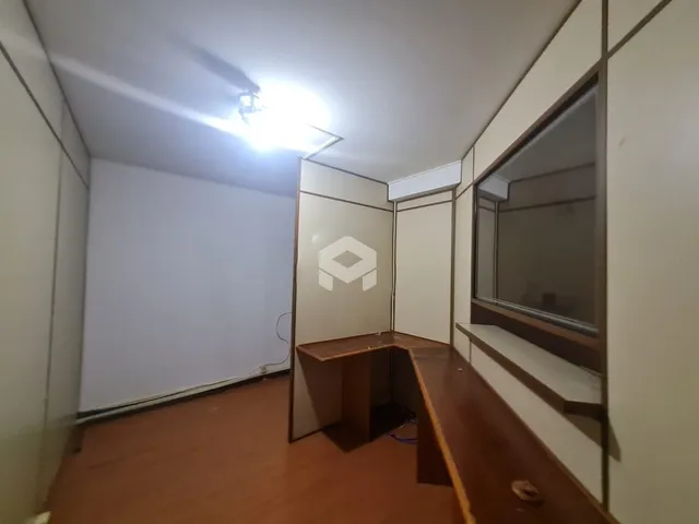 Interior de uma sala com piso de madeira e paredes brancas.