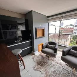Foto interna de uma sala de estar com sofá e móveis escuros.