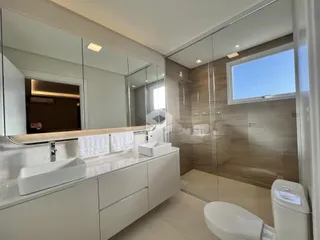 Banheiro moderno com box de vidro e revestimento de madeira.