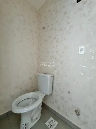 Foto de um banheiro interno com papel de parede e vaso sanitário branco.