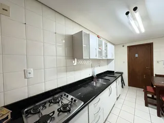 Foto de uma cozinha com armários brancos e bancada escura.