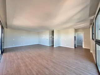 Sala de estar ampla com piso de madeira clara.