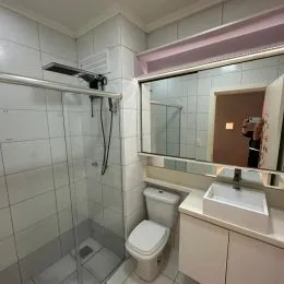 Foto de um banheiro com revestimento de azulejos brancos e box de vidro.