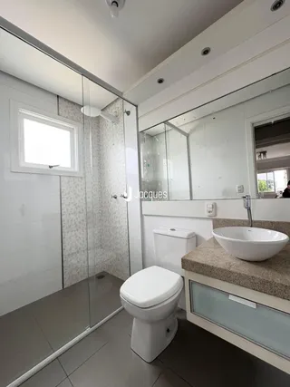 Banheiro moderno com box de vidro e piso de cerâmica.