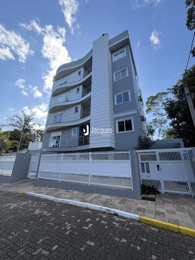 Fachada de um prédio residencial em Lajeado, Brasil, com varanda e portão branco.
