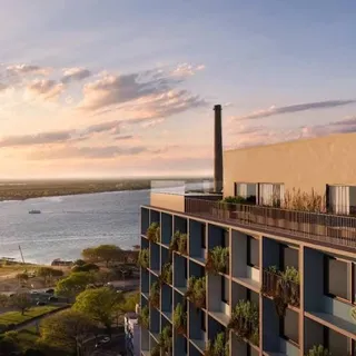 Vista externa de um edifício com paisagem de água ao fundo.