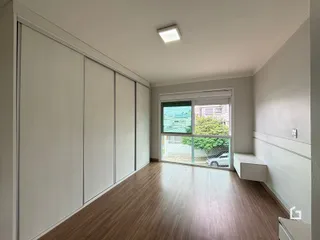 Ambiente interno de uma sala com piso de madeira e armários embutidos.