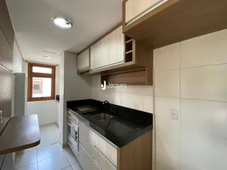 Vista da cozinha com armários de madeira e bancada escura.