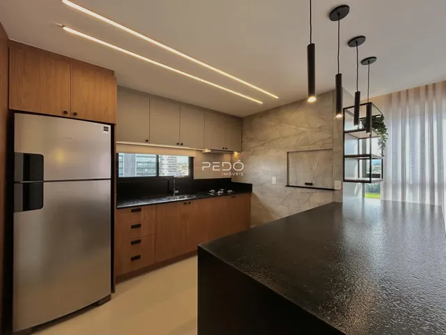 Vista de uma cozinha moderna com armários de madeira e bancadas escuras.