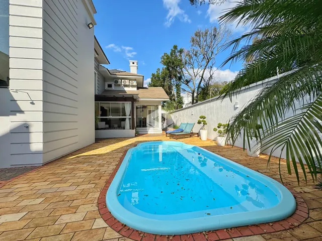 Foto da área externa com piscina e jardim de uma residência em Lajeado.