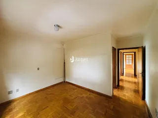 Interior de uma sala com piso de madeira clara e paredes brancas.