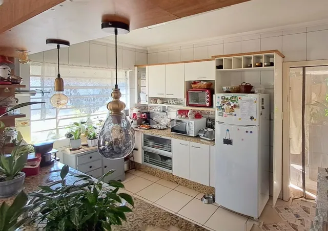 Foto de uma cozinha com armários brancos e piso de cerâmica.