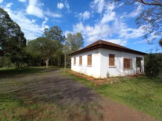 Fachada de uma casa branca com telhado de telhas em um terreno gramado.