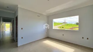 Ambiente interno com parede branca e grande janela mostrando a paisagem externa.