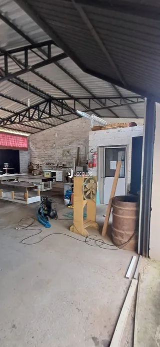 Vista externa de uma estrutura em construção com telhado de metal.