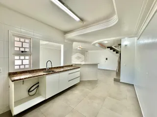 Foto de uma cozinha com armários brancos e piso claro.