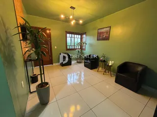 Sala de estar com paredes verdes e piso de cerâmica em um imóvel no Brasil.
