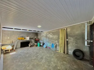 Interior de uma sala em construção com teto exposto e materiais de obra.