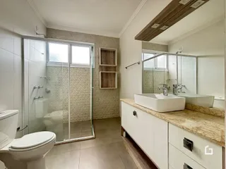 Foto de um banheiro com box de vidro e bancada de mármore.