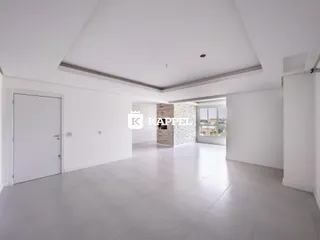 Sala ampla com piso claro e parede de tijolos expostos.