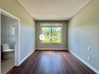 Sala de estar com piso de madeira e grande janela mostrando a vegetação externa.