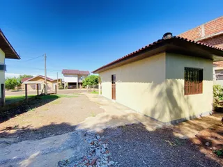 Fachada de uma casa em Lajeado, Brasil, com terreno gramado e acesso de terra.
