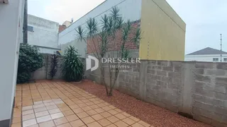 Área externa com piso de cerâmica e jardim lateral em Lajeado.
