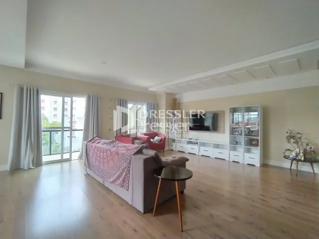 Sala de estar com piso de madeira clara e grandes janelas.
