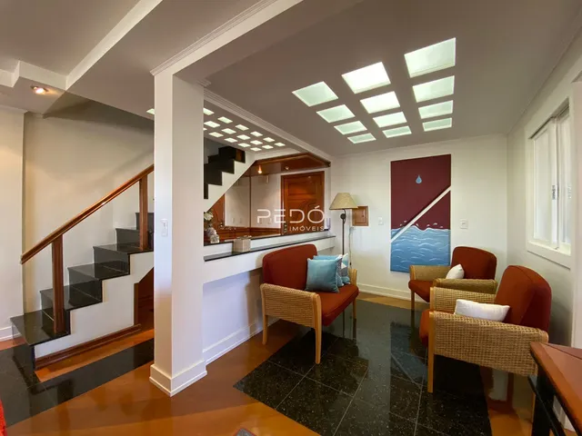 Ambiente interno de uma sala de estar com escadaria e decoração moderna.