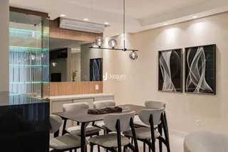 Foto de uma sala de jantar moderna com mesa escura e cadeiras cinzas.
