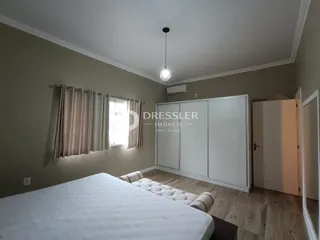 Quarto com cama e guarda-roupa em ambiente claro.