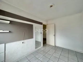 Interior de uma sala com piso de cerâmica e parede cinza.