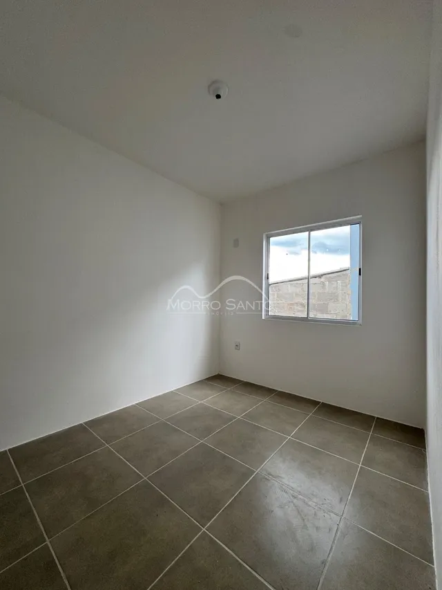 Vista interna de um cômodo com piso de cerâmica e janela.