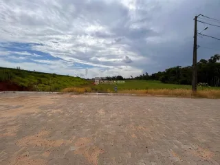 Vista externa de um terreno aberto com vegetação rasteira sob um céu nublado.