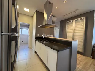 Cozinha moderna com armários brancos e bancada escura em imóvel no Brasil.
