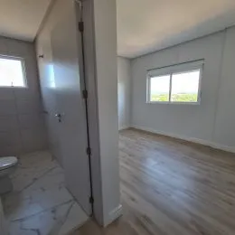 Foto de um corredor interno com piso de madeira e uma janela.