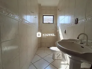 Banheiro com revestimento de azulejos brancos e pia branca.