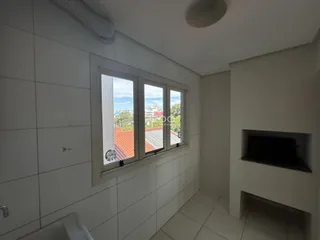 Uma sala interna com paredes brancas e janelas voltadas para um telhado de telhas.
