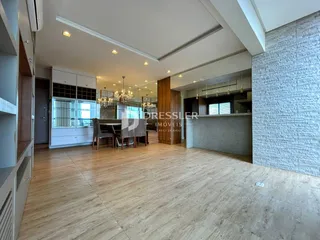 Ambiente interno de uma sala de estar com piso de madeira clara e decoração moderna.
