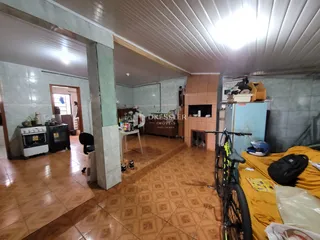 Interior de uma sala com piso de cerâmica e parede de tijolos exposta.