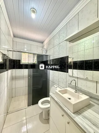 Banheiro com revestimento de azulejos brancos e bancada de mármore clara.