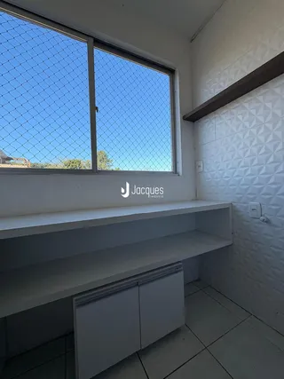 Interior de um cômodo com janela e prateleira em uma residência.