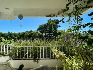 Vista de uma varanda com vegetação exuberante e grade de segurança.