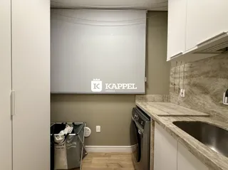 Vista interna de uma cozinha com bancada e área de lavanderia.