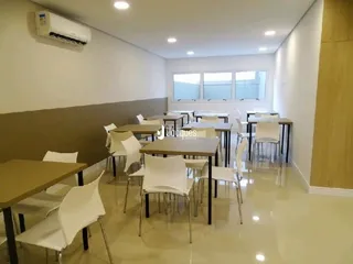 Ambiente interno de uma sala com mesas e cadeiras em um imóvel.