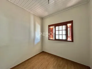 Interior de um cômodo com piso de madeira e janela.