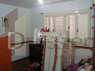 Interior de uma sala com paredes claras e piso de madeira.